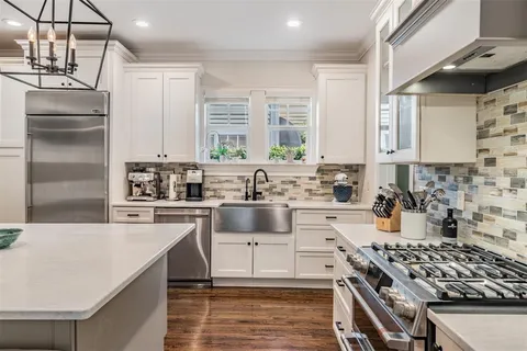 a kitchen with stainless steel appliances a stove a sink dishwasher a refrigerator and cabinets with wooden floor