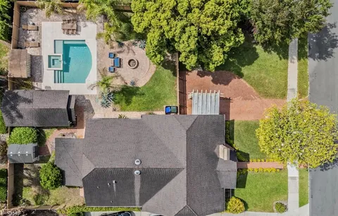 an aerial view of a house with a yard and large trees