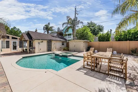 a view of a backyard with table and chairs potted plants and wooden fence