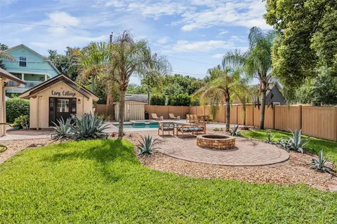 a backyard of a house with plants and large tree