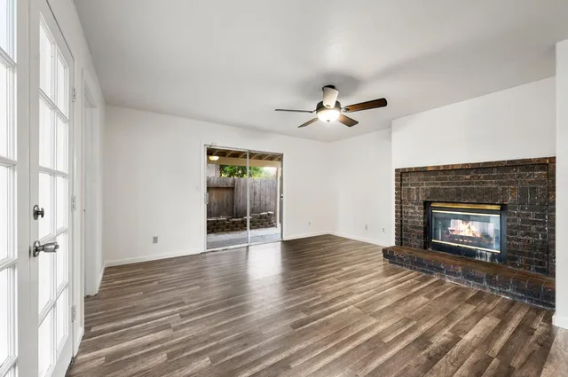 an empty room with wooden floor fireplace and windows