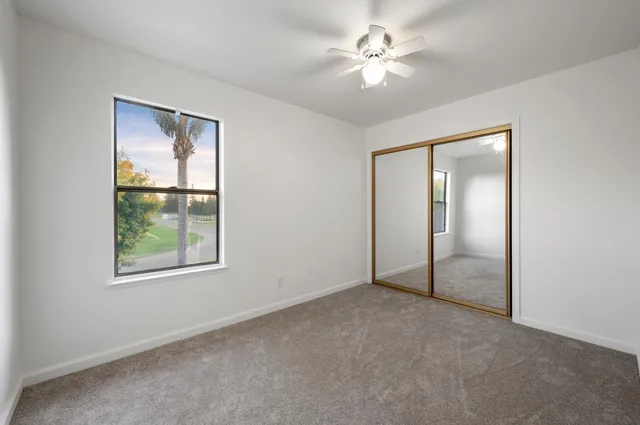 an empty room with windows and fan