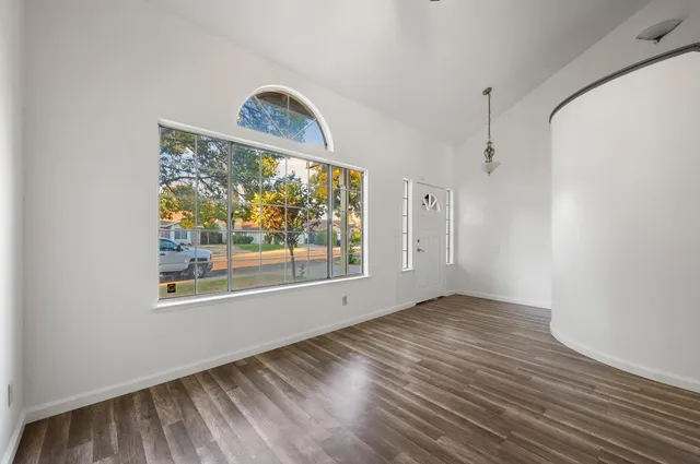 a view of an empty room with a window and wooden floor