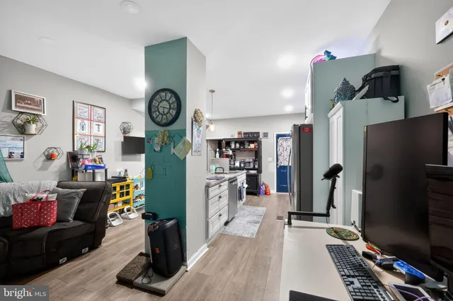 a living room with furniture a flat screen tv and a refrigerator