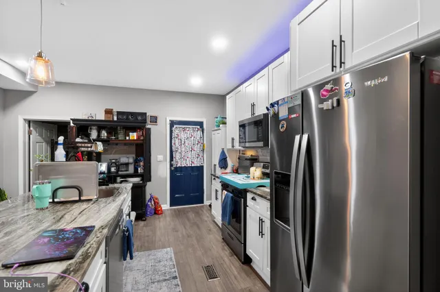a kitchen with stainless steel appliances granite countertop a refrigerator a stove and a sink