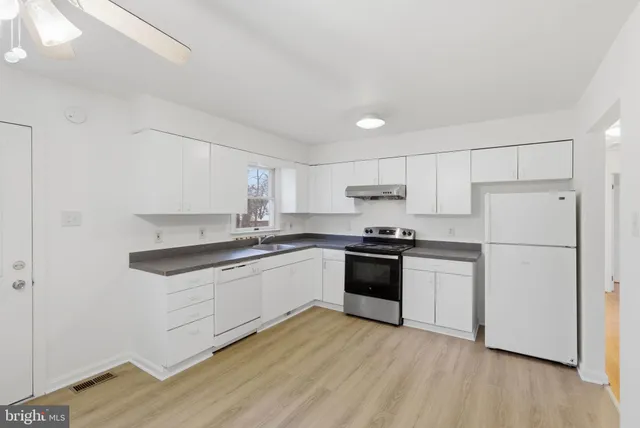 a kitchen with granite countertop a sink a cabinets and wooden floor