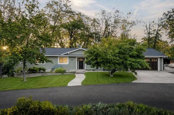a front view of a house with a garden and trees