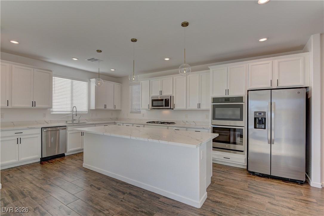727 Foreign Reef Way Las Vegas, NV 89138 - Photo 7 of 25 Kitchen featuring stainless steel appliances, white cabinets, decorative light fixtures, light stone countertops, and recessed lighting