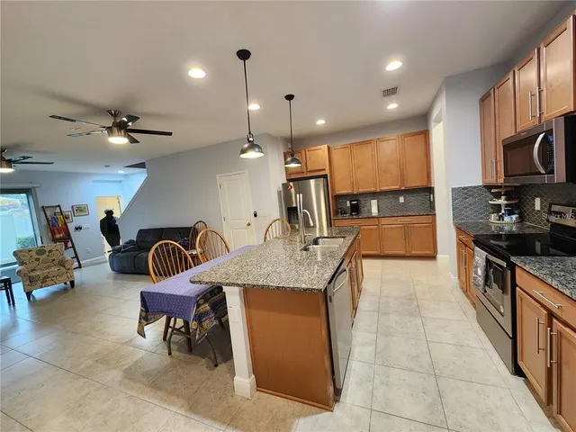 a kitchen with kitchen island granite countertop a stove a sink a dining table and chairs