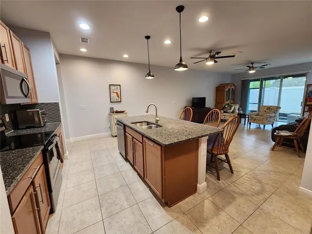 a kitchen with granite countertop a table chairs and a refrigerator
