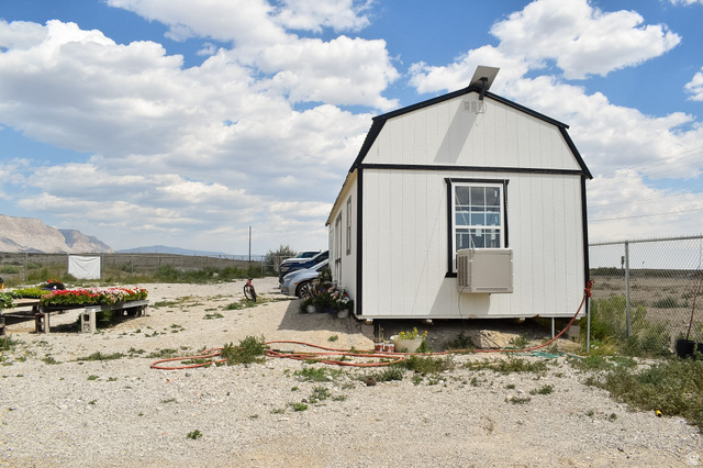 345 North Main Street Clawson, UT 84516 - Photo 15 of 17 White siding structure with a gambrel-style roof, featuring a single-pane window with black trim