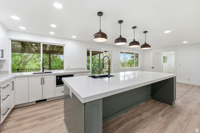 871 Bonita Way Centerville, UT 84014 - Photo 4 of 61 Spacious kitchen featuring a large central island with a light-toned countertop, white cabinetry with black hardware, wood-finish flooring, and recessed ceiling lights