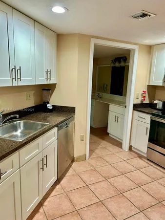 a kitchen with granite countertop white cabinets and white appliances