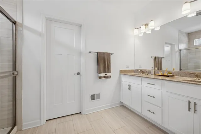 a spacious bathroom with a granite countertop sink a mirror and shower