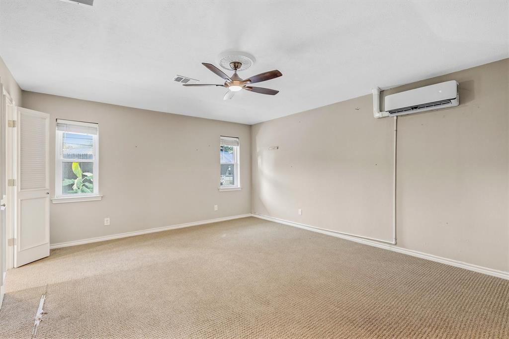 4436 Thunder Road Dallas, TX 75244 - Photo 23 of 33 Neutral wall finishes, textured carpeting, two windows, ceiling fan with light fixture, and wall-mounted air conditioning unit