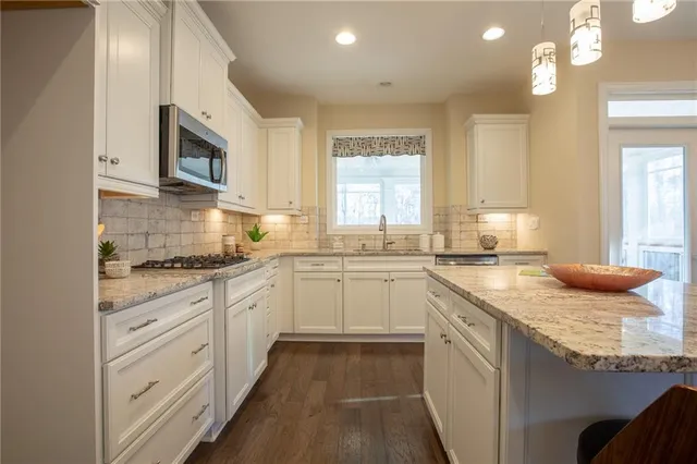 a kitchen with stainless steel appliances granite countertop a stove a sink and a microwave