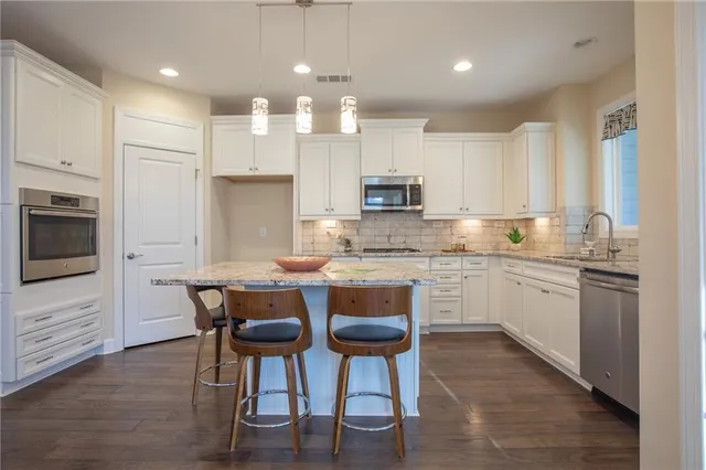 a kitchen with kitchen island granite countertop wooden floors and white cabinets