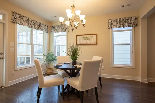 a dining room with wooden floor a chandelier a glass table and chairs