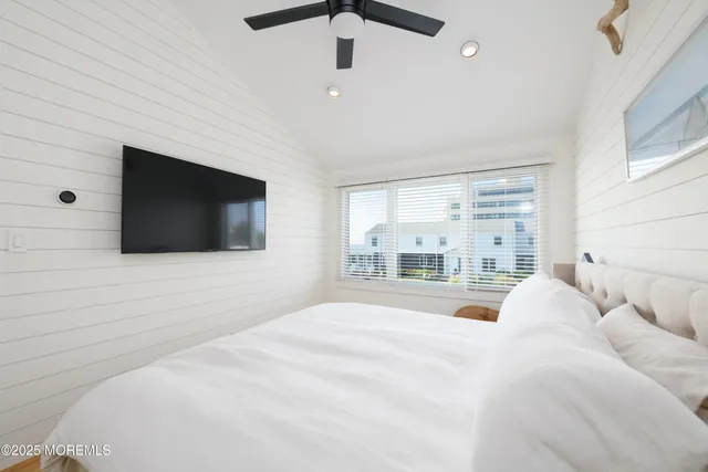 a bedroom with a large bed a flat screen tv and a chandelier