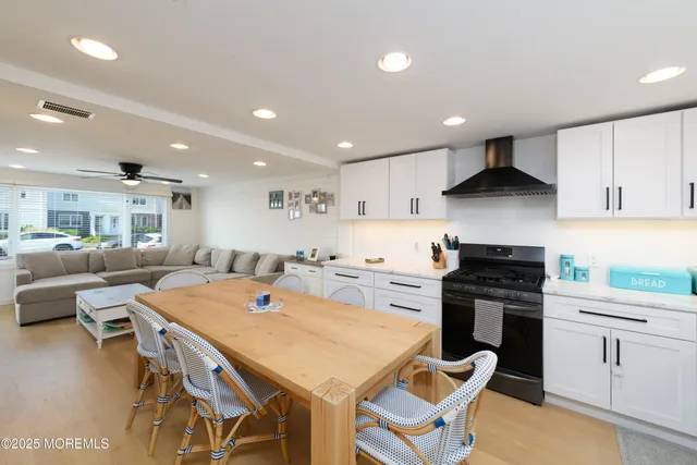 a kitchen with stainless steel appliances kitchen island granite countertop a stove a sink a dining table and chairs