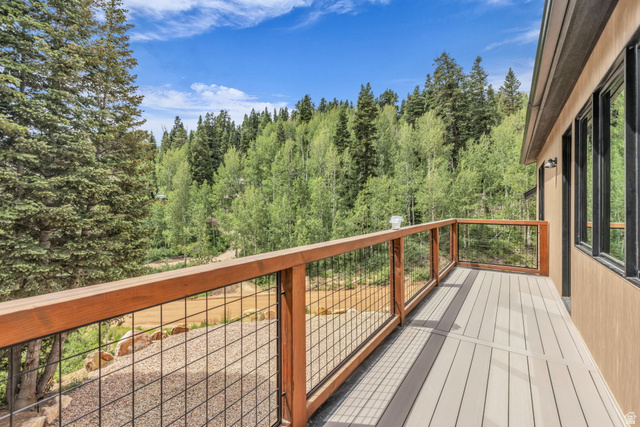 1766 West Tollgate Cyn Road Coalville, UT 84017 - Photo 38 of 59 Spacious outdoor deck featuring composite decking, wood-toned railings with metal infill, and exterior wall sconces