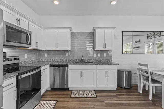 a kitchen with stainless steel appliances granite countertop a stove a sink and a microwave