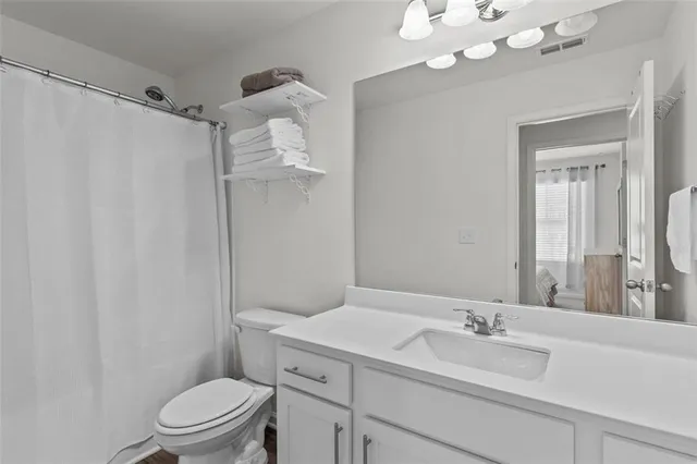 a bathroom with a granite countertop sink a toilet and a mirror