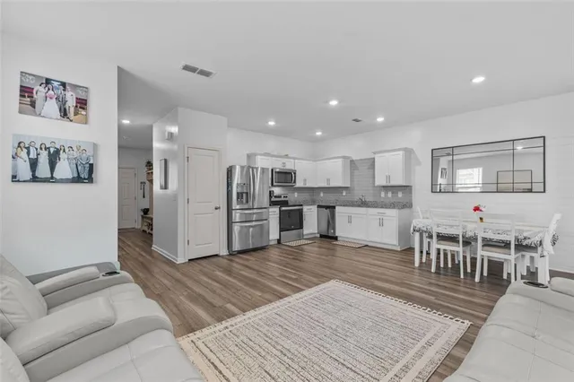 a living room with stainless steel appliances furniture and a kitchen view