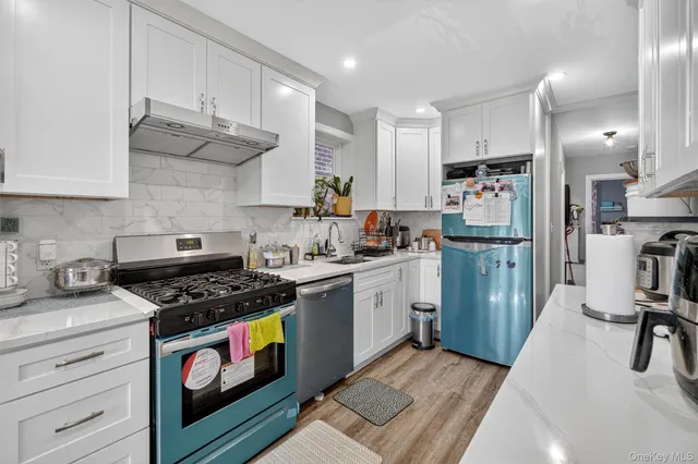 a kitchen with granite countertop a stove a sink dishwasher and a refrigerator with wooden floor