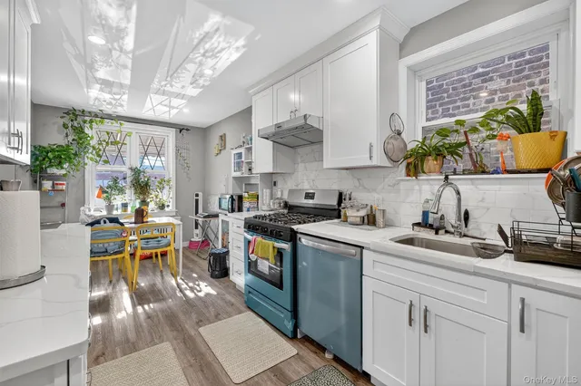 a kitchen with stainless steel appliances granite countertop a sink dishwasher a stove a dining table and chairs with wooden floor