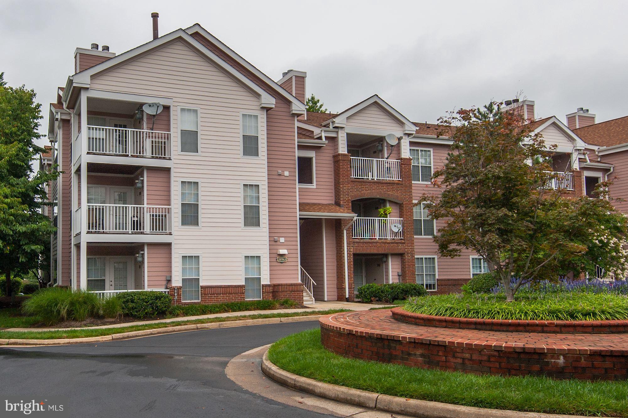 20963 Timber Ridge Terrace, Unit 202 Ashburn, VA 20147 - Photo 1 of 22 a front view of a house with a yard