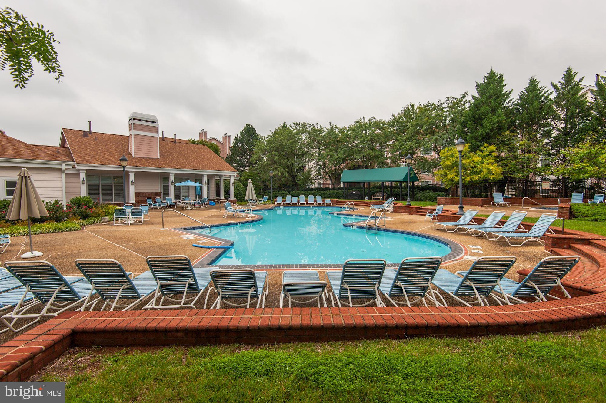 20963 Timber Ridge Terrace, Unit 202 Ashburn, VA 20147 - Photo 18 of 22 a view of a swimming pool and lounge chairs in back yard of the house