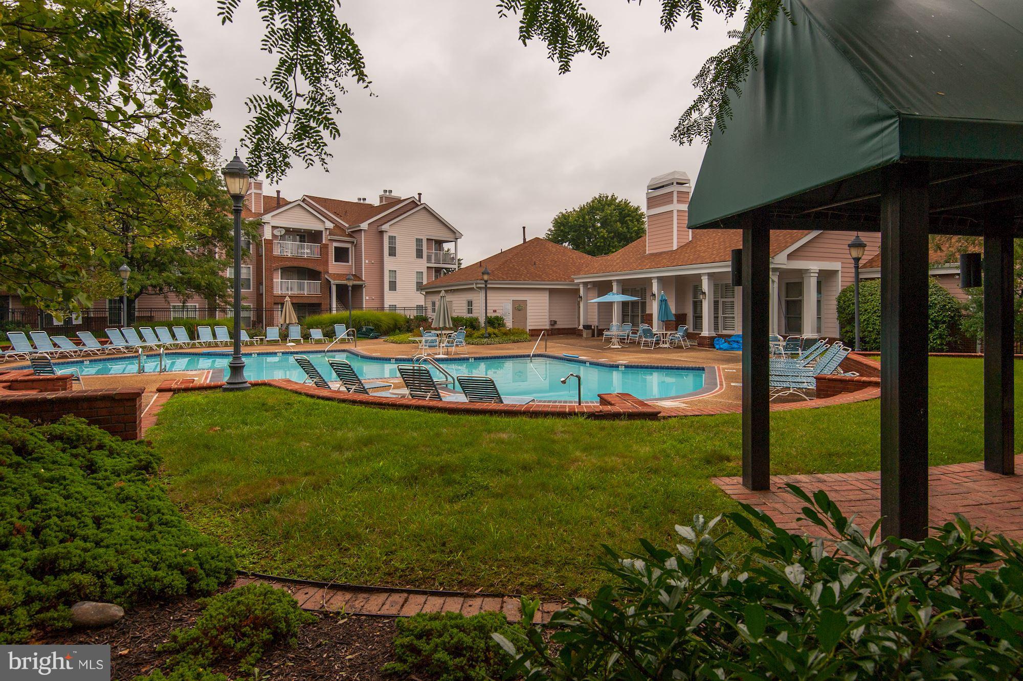 20963 Timber Ridge Terrace, Unit 202 Ashburn, VA 20147 - Photo 19 of 22 a front view of a house with a yard table and chairs
