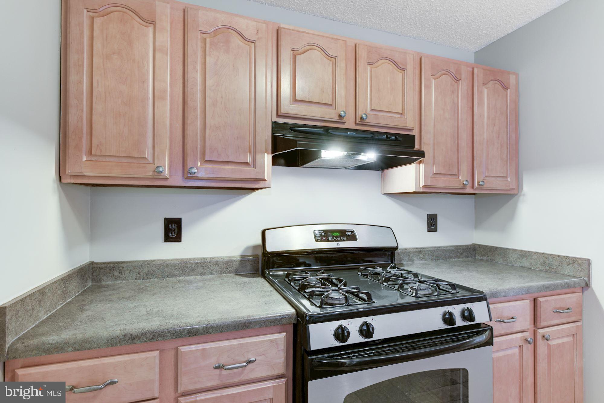 20963 Timber Ridge Terrace, Unit 202 Ashburn, VA 20147 - Photo 5 of 22 a kitchen with granite countertop a stove and a white cabinets