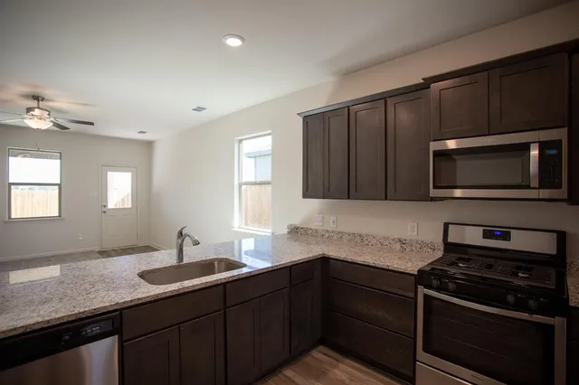 a kitchen with sink a microwave a stove and cabinets
