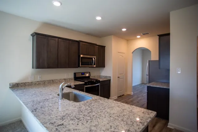 a kitchen with stainless steel appliances granite countertop a sink stove and microwave