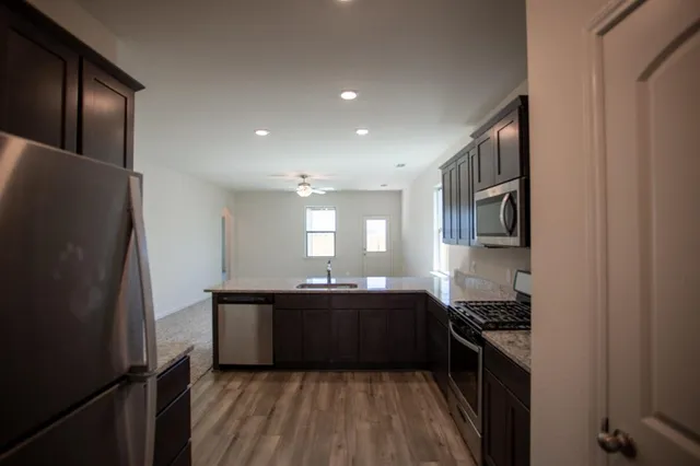 a kitchen with granite countertop a refrigerator stove and sink