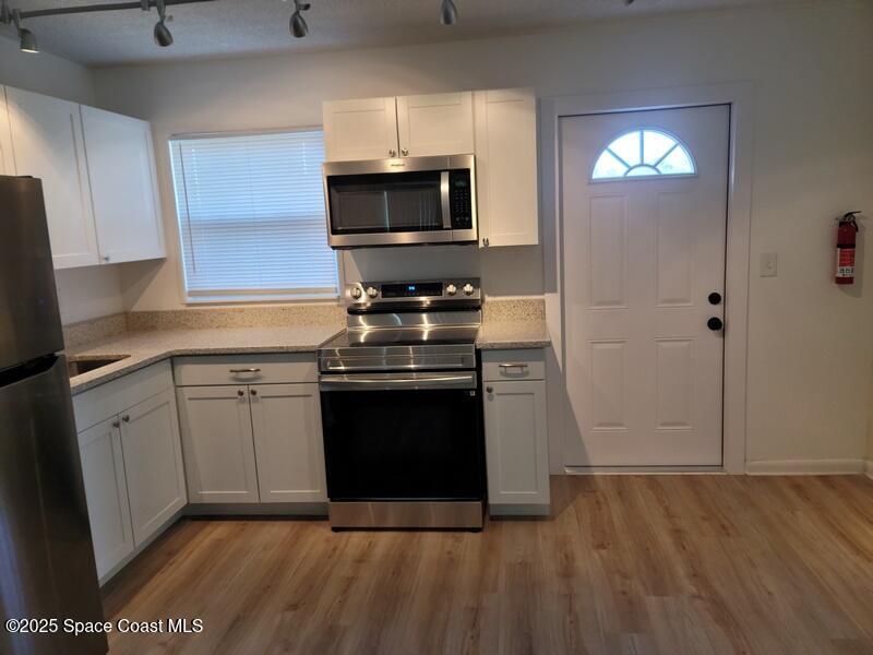 1700 Chaucer Road Titusville, FL 32780 - Photo 15 of 15 a kitchen with stainless steel appliances granite countertop a stove a microwave and a refrigerator