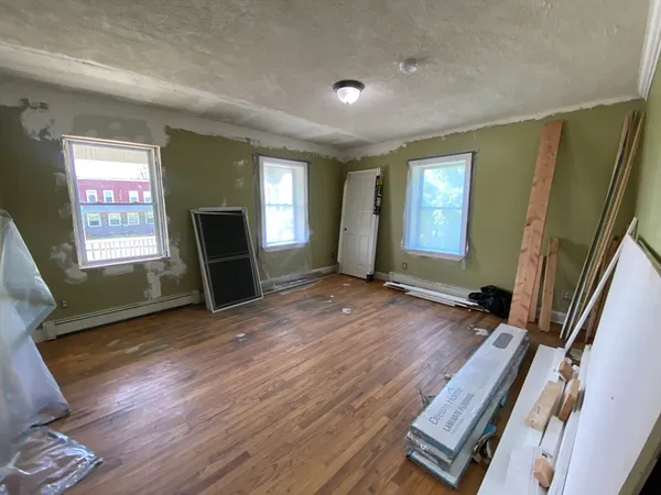 a view of an empty room with a window and wooden floor