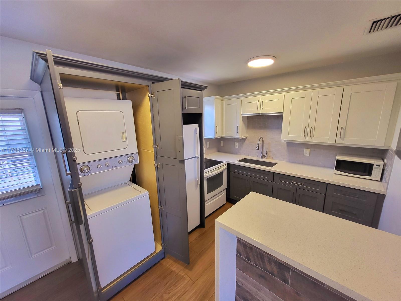 2355 Southwest 27th Street, Unit 4 Miami, FL 33133 - Photo 1 of 25 a kitchen with a refrigerator a stove top oven and cabinets