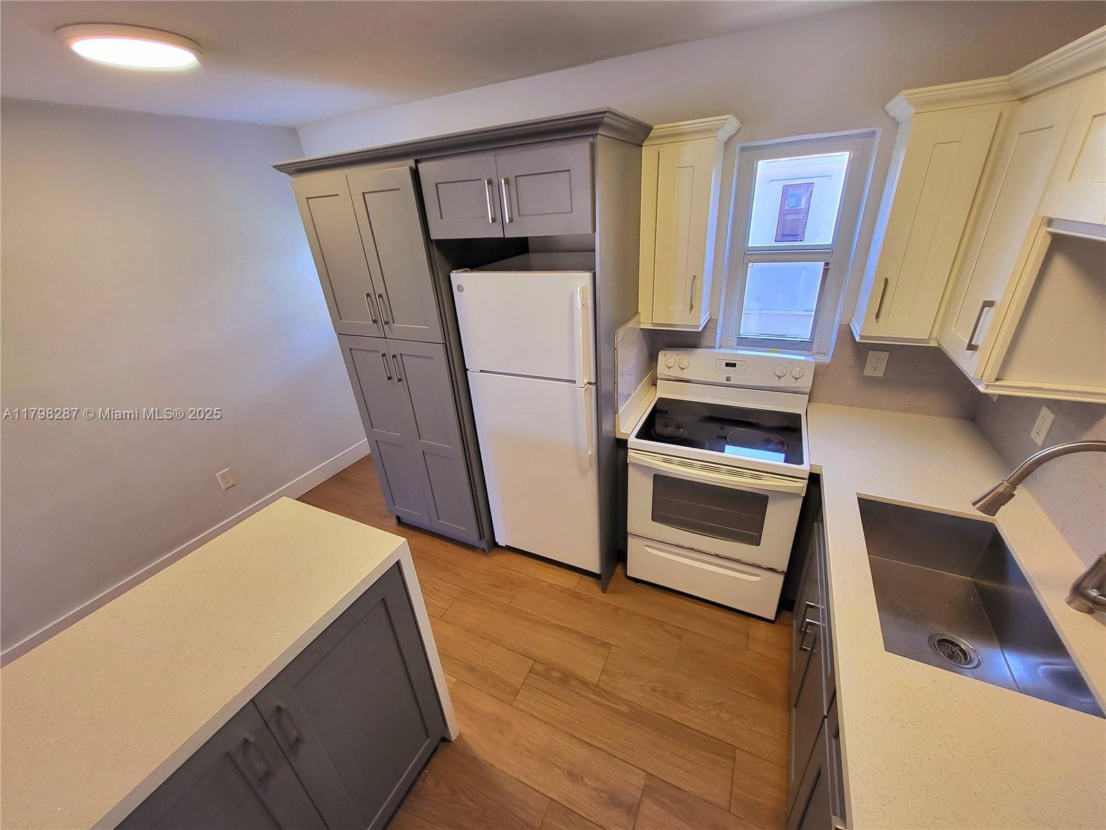 2355 Southwest 27th Street, Unit 4 Miami, FL 33133 - Photo 11 of 25 a kitchen with wooden floor and electronic appliances