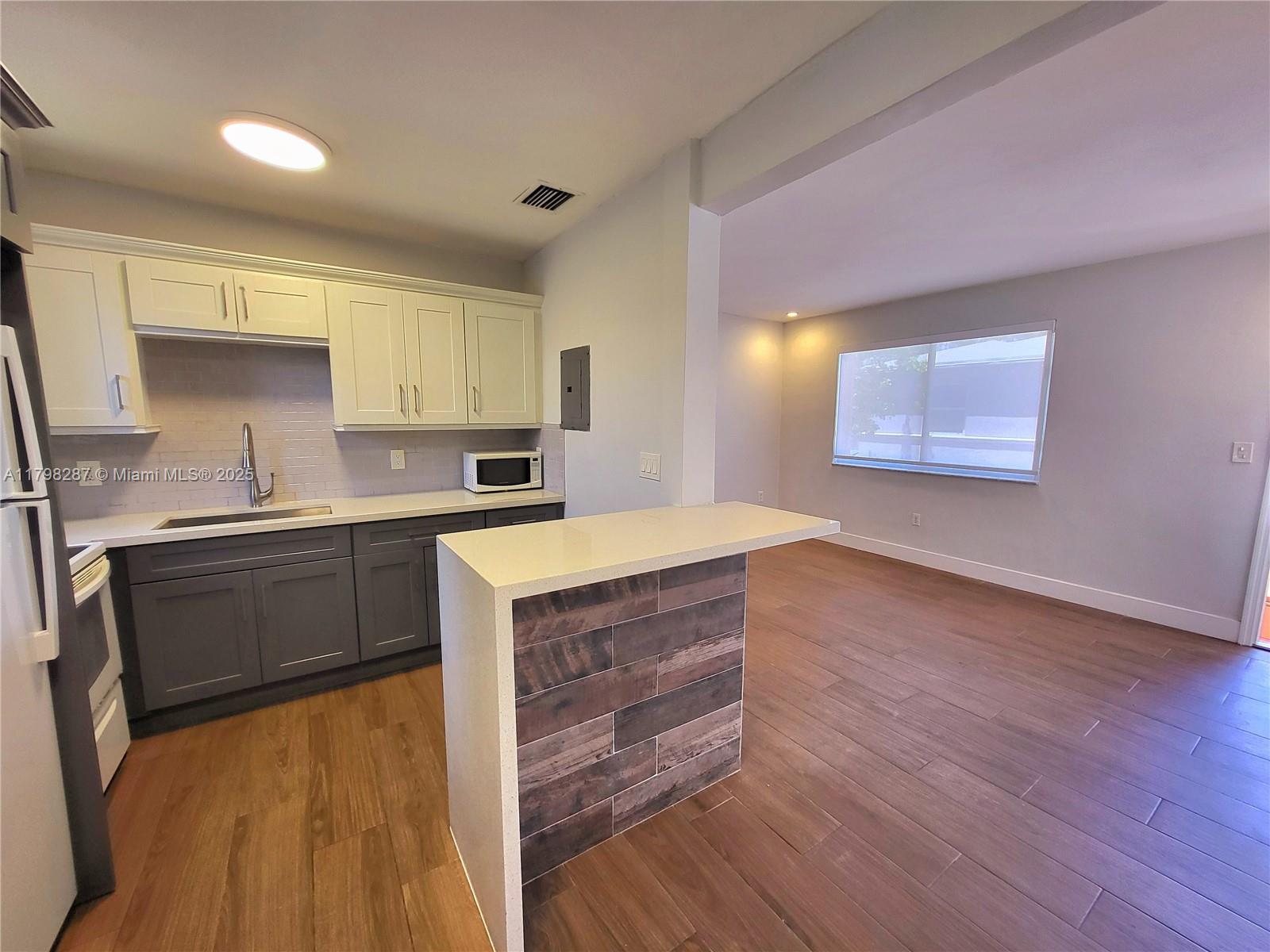 2355 Southwest 27th Street, Unit 4 Miami, FL 33133 - Photo 12 of 25 a kitchen with wooden floors and wooden cabinets