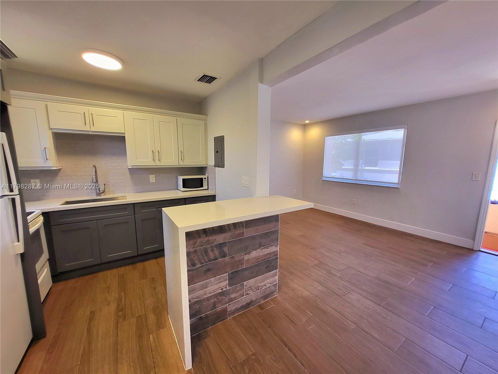 2355 Southwest 27th Street, Unit 4 Miami, FL 33133 - Photo 18 of 25 a kitchen with wooden floors and white appliances