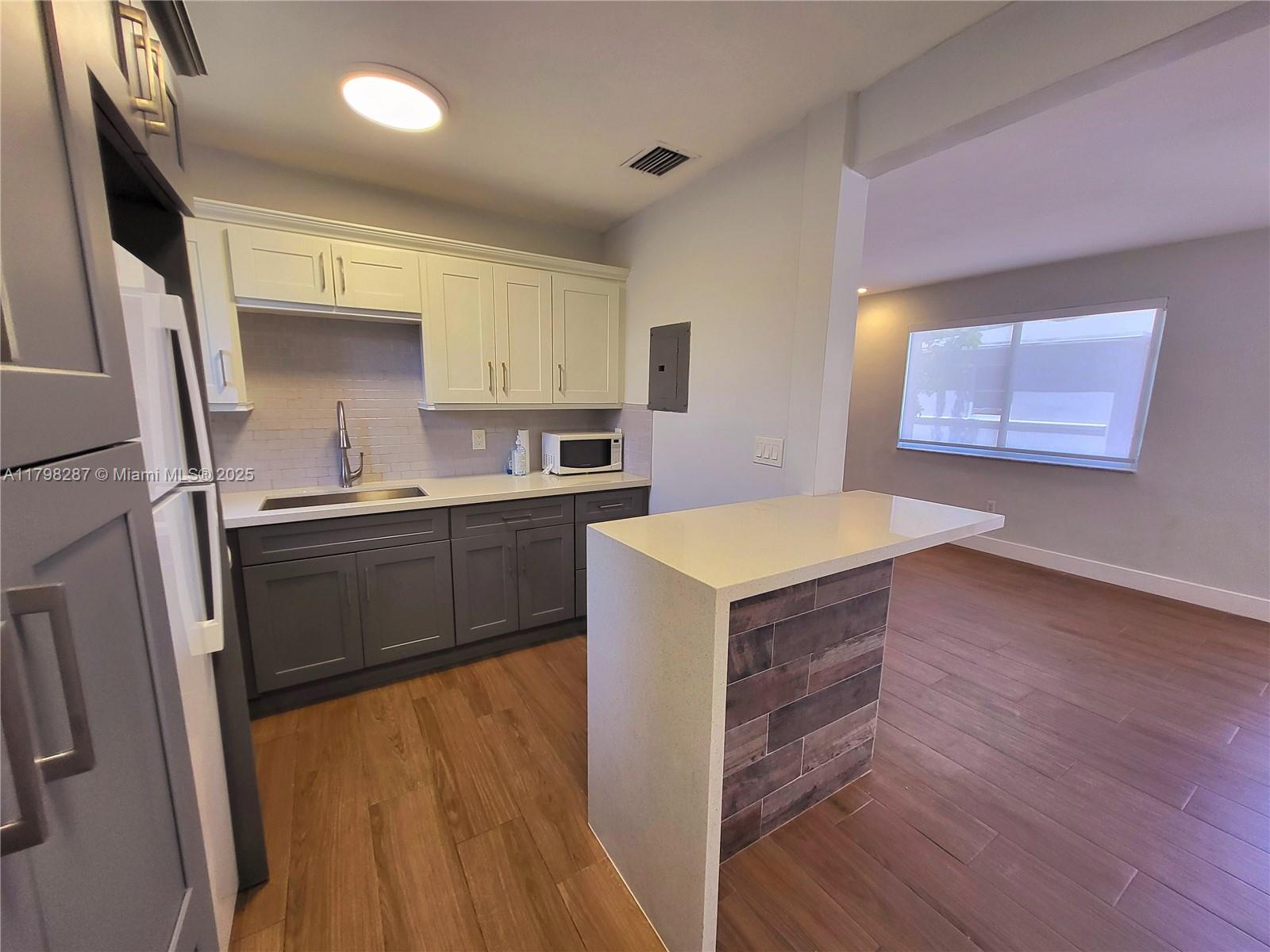 2355 Southwest 27th Street, Unit 4 Miami, FL 33133 - Photo 19 of 25 a kitchen with a sink a stove cabinets and a wooden floor