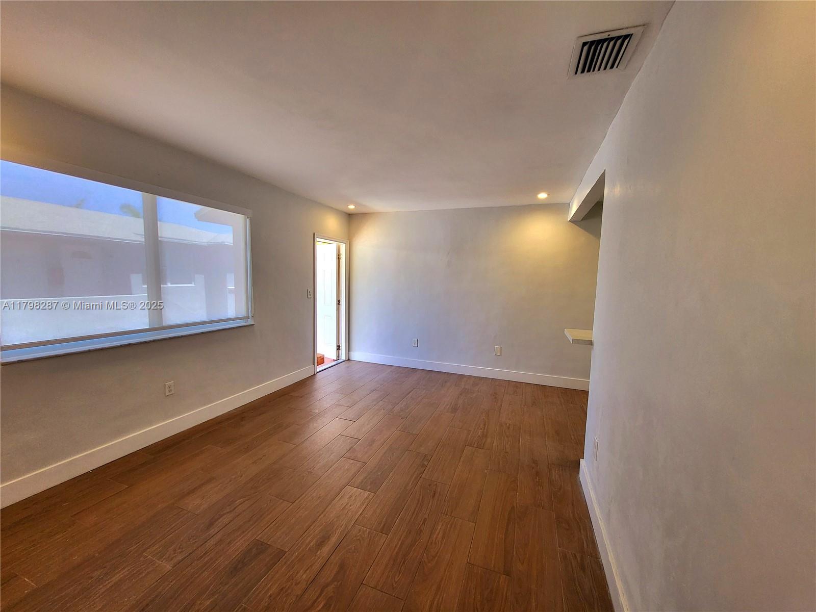 2355 Southwest 27th Street, Unit 4 Miami, FL 33133 - Photo 21 of 25 a view of an empty room with wooden floor and a window