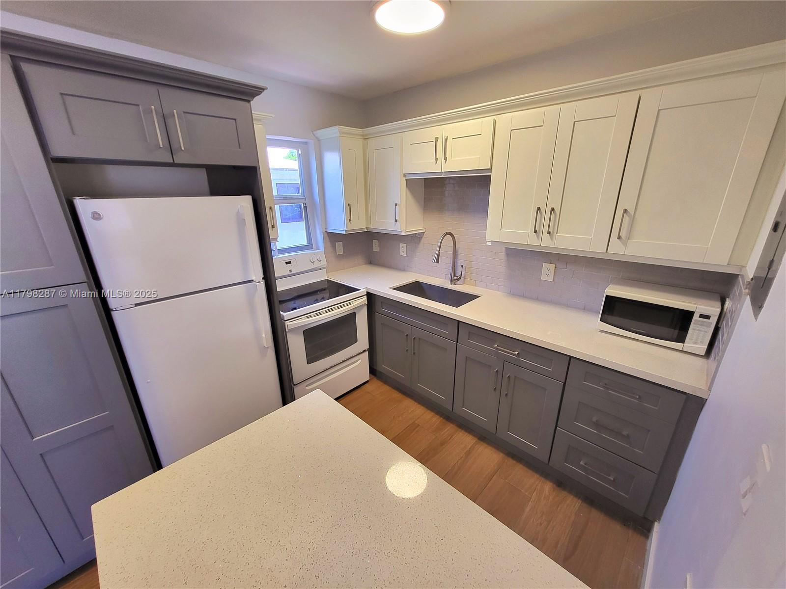 2355 Southwest 27th Street, Unit 4 Miami, FL 33133 - Photo 22 of 25 a kitchen with stainless steel appliances a refrigerator sink and cabinets