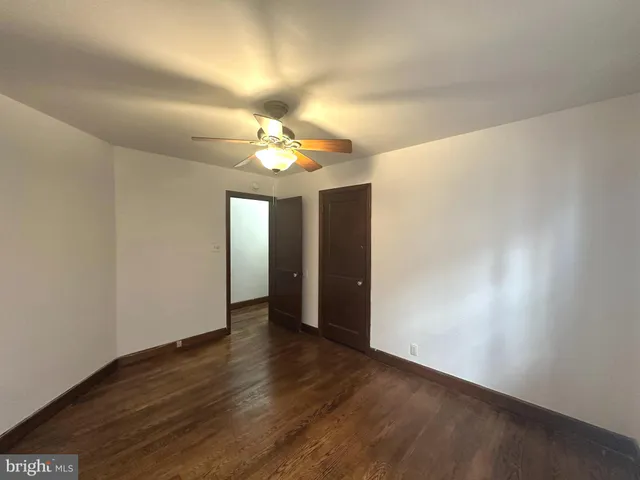 an empty room with wooden floor and chandelier fan