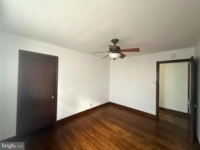 an empty room with wooden floor closet and windows
