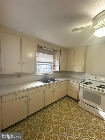 a large white kitchen with a stove a sink and a window