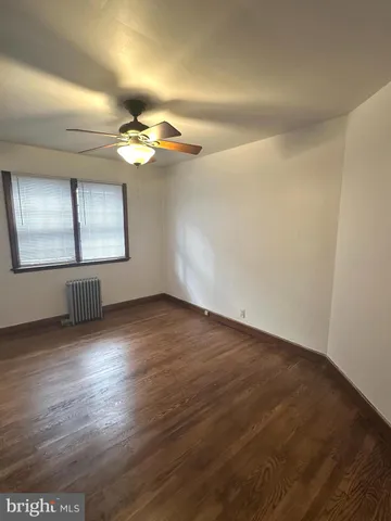 an empty room with wooden floor chandelier fan and windows